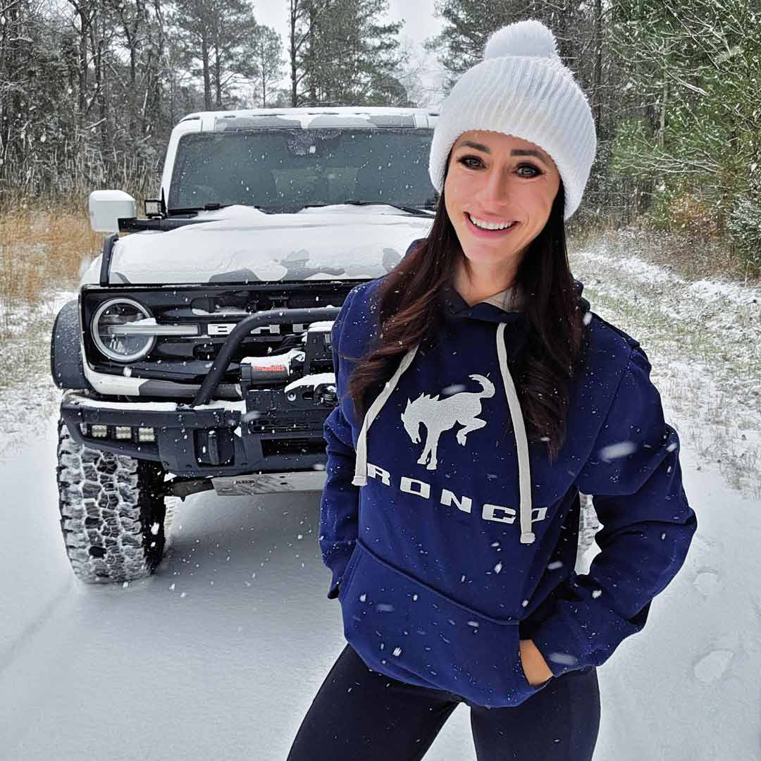 woman in snow wearing a navy Bronco hoodie