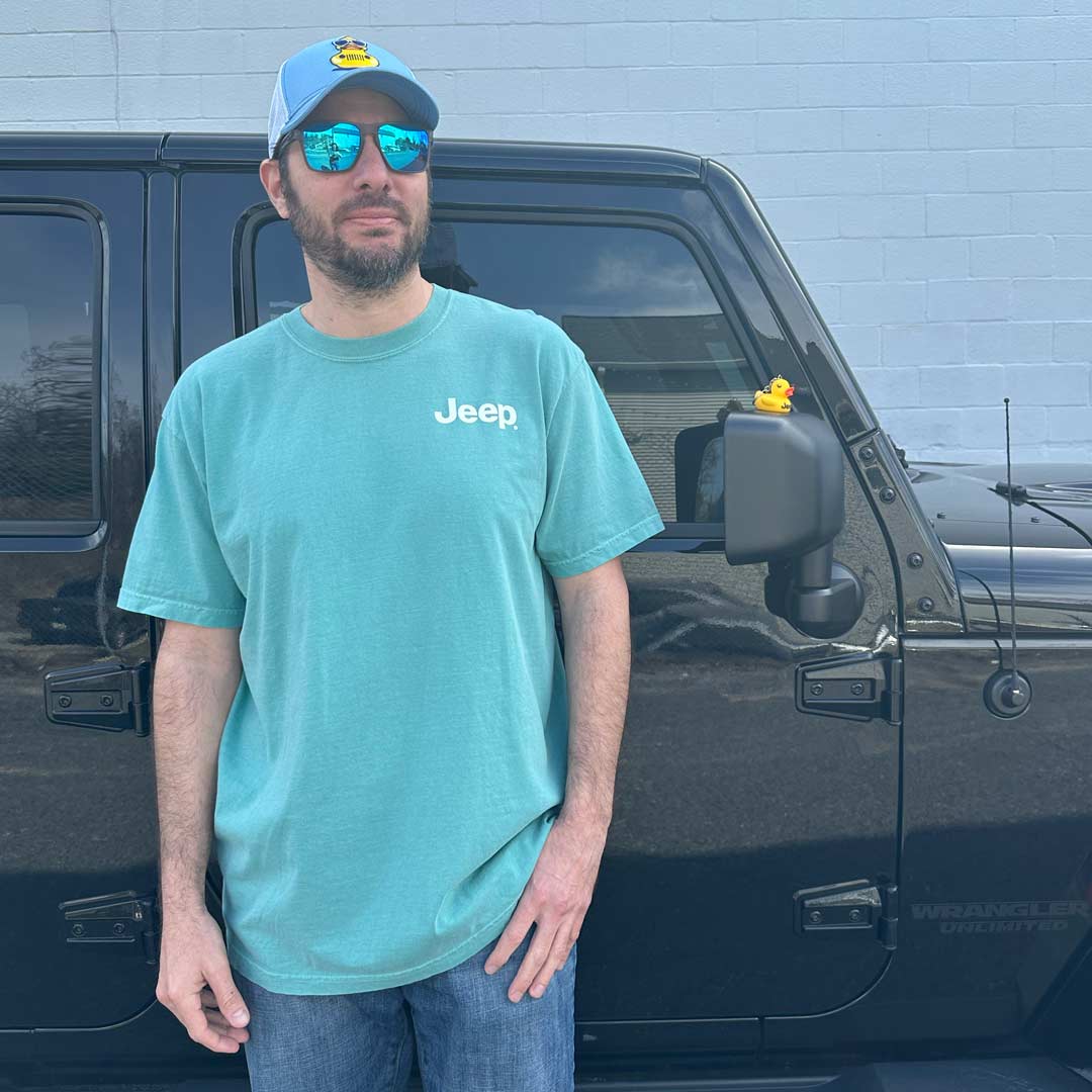man wearing a teal t-shirt with Jeep logo on left chest and blue Jeep duck hat