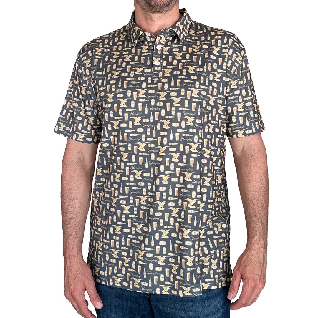 Man wearing Yuengling dark grey polo with a beer bottle, can, logo and eagle repeat pattern,