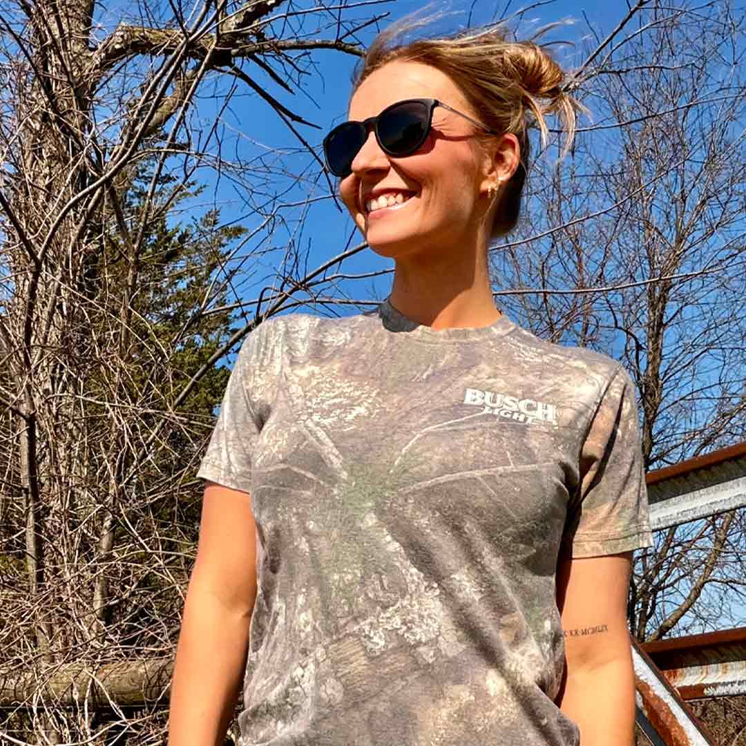 woman in outdoor scene wearing a camo Busch Light t-shirt