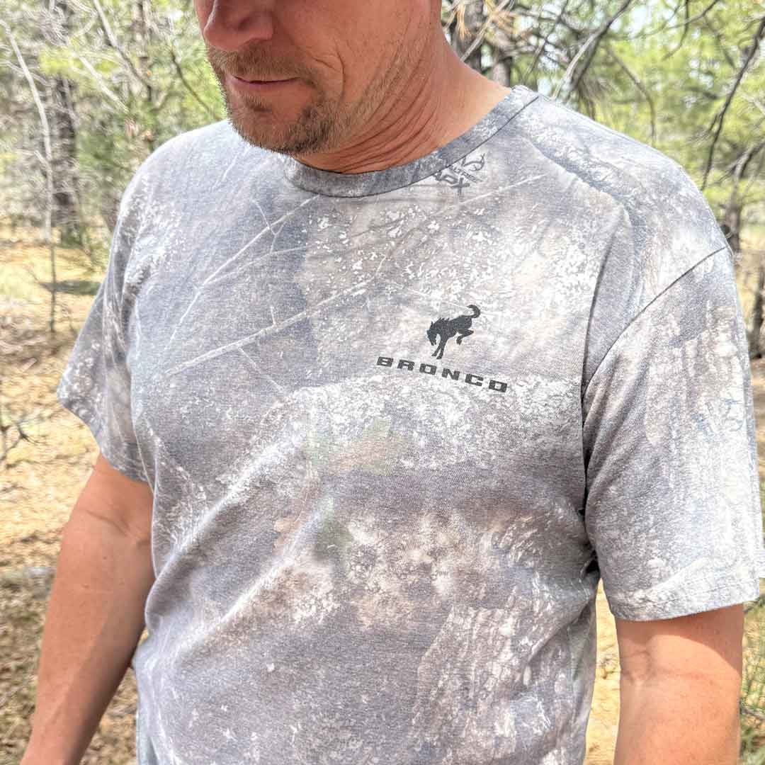 Man in wooded environment wearing a camo Ford Bronco shirt