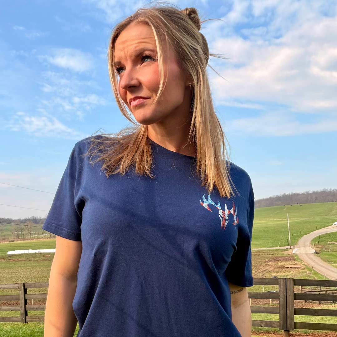 woman on a farm wearing a navy blue shirt with an American flag Buck Wear logo