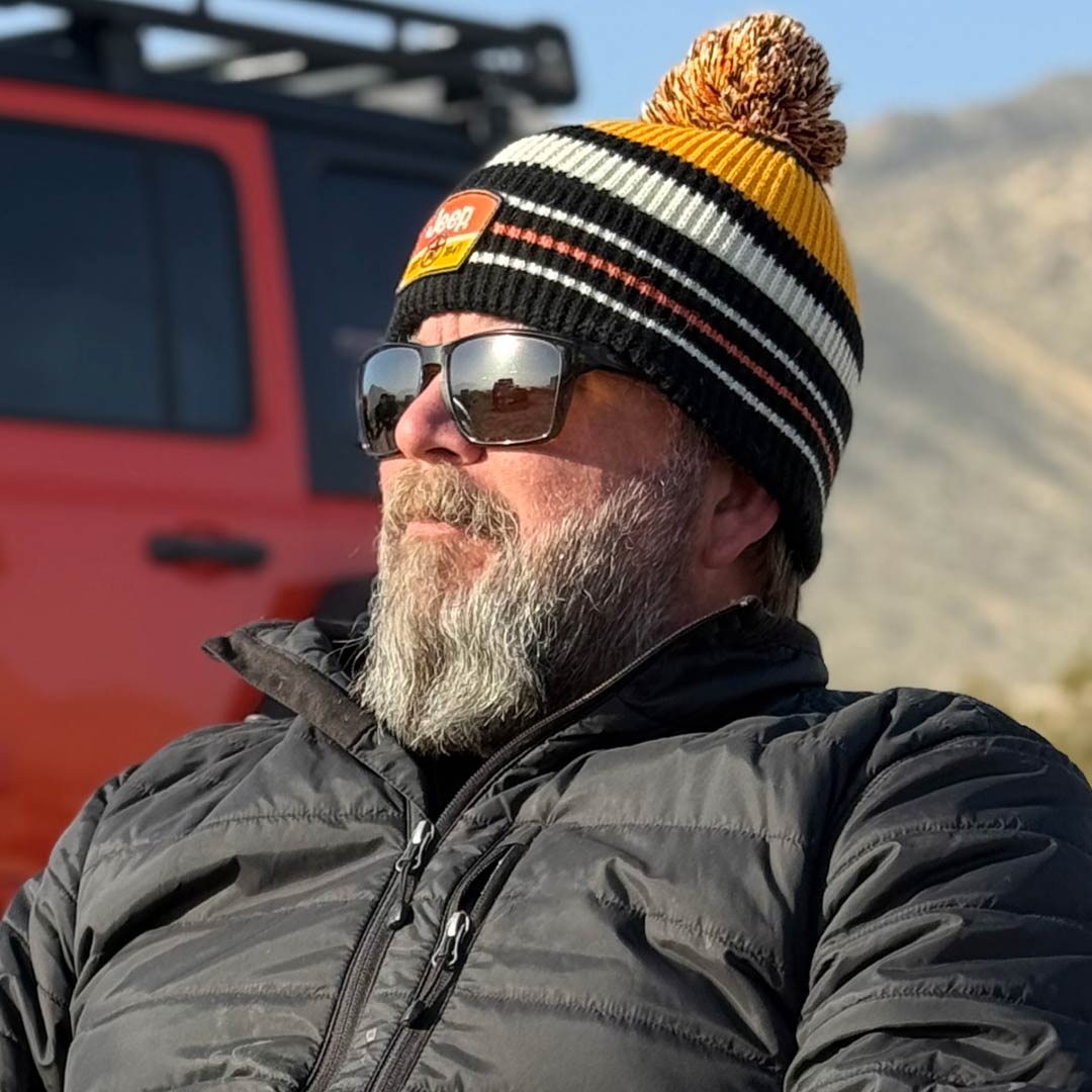 man with beard wearing sunglasses and a black and orange knit Jeep hat