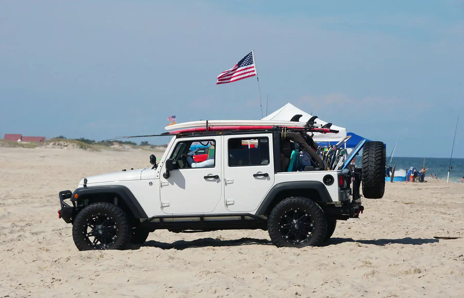 Jeep on a beach with a surfboard on it