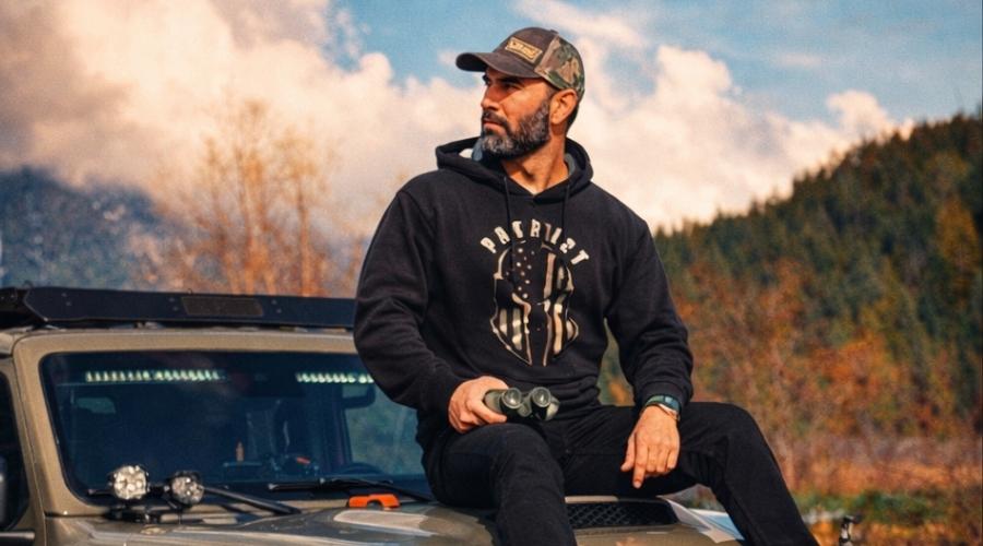 man sitting on the hood of his jeep vehicle