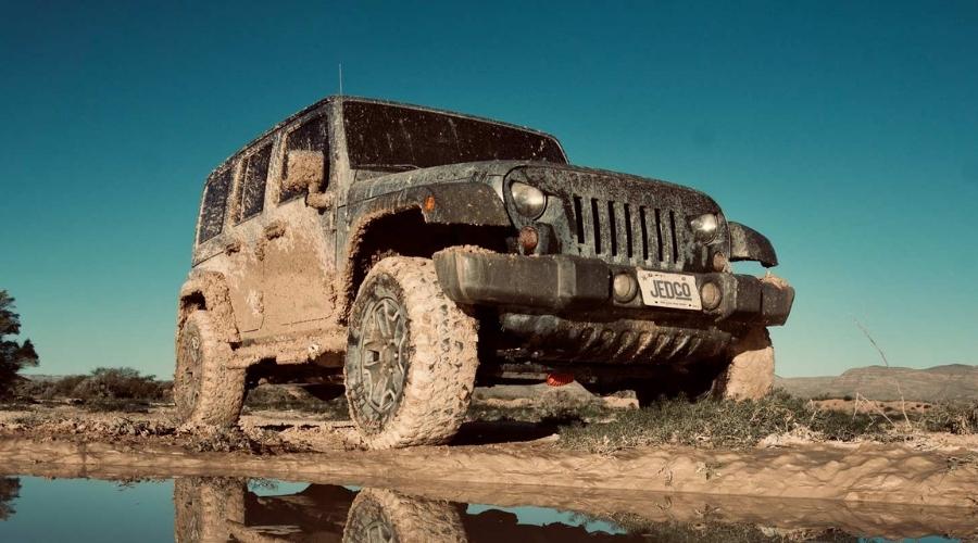 muddy jeep driving over mud
