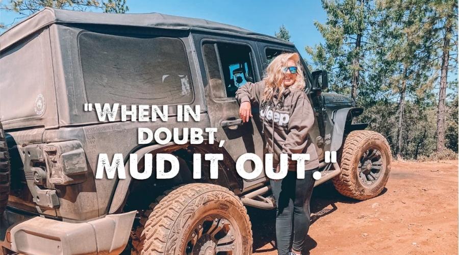 Woman standing next to her muddy jeep