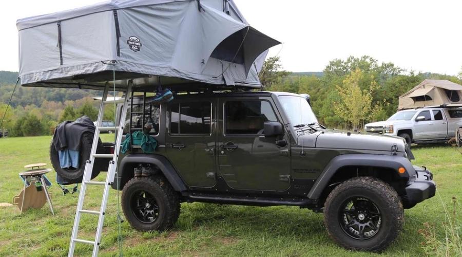 Jeep camping with tent above it