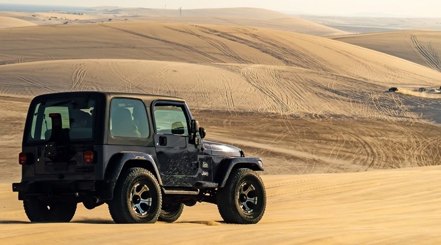 Green jeep driving in the sand