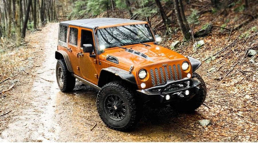 Orange jeep riding on a off road trail