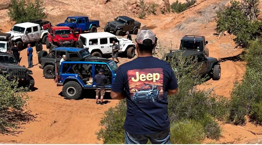man wearing a jeep shirt towering over and looking at jeeps
