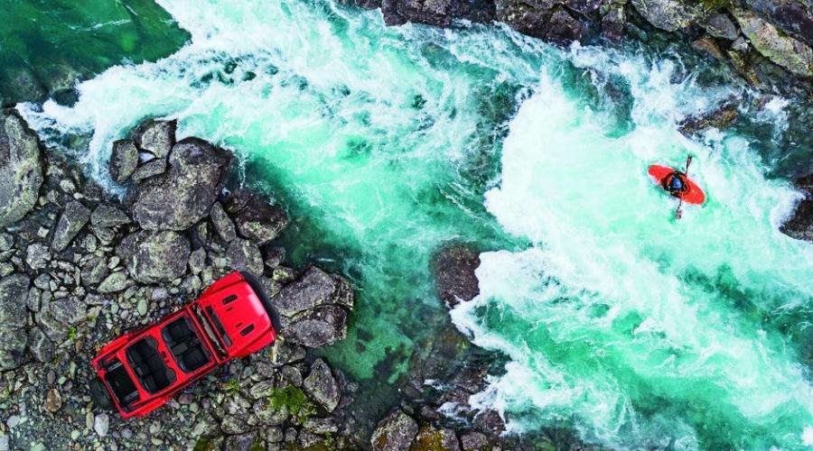 Red jeep next to a river