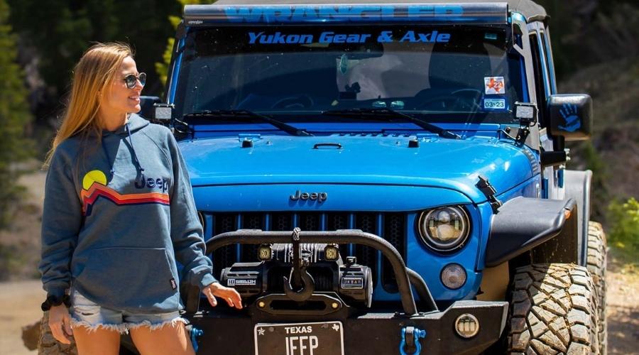 Woman standing next to a blue jeep
