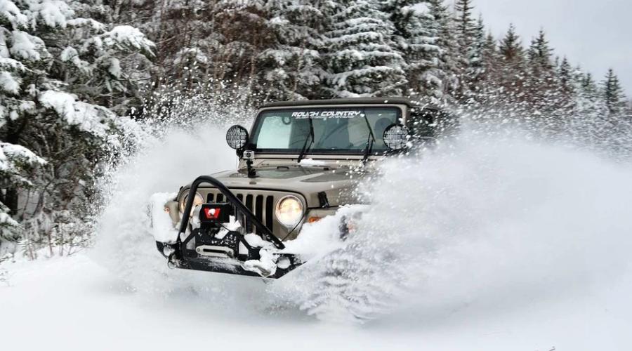 Green Jeep cruising through snow
