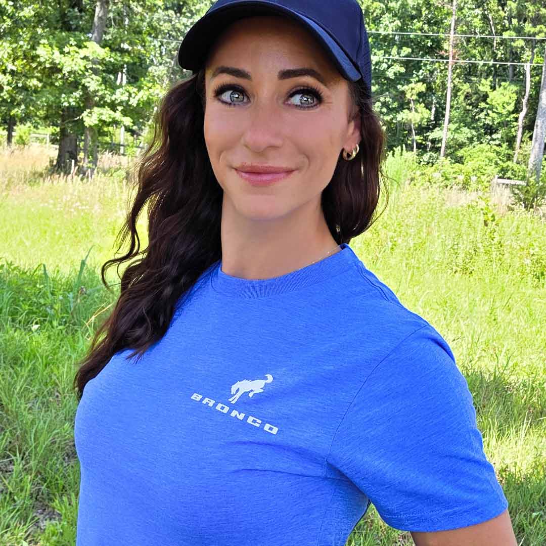 Woman wearing blue Bronco Sasquatch T-Shirt in a grassy environment 