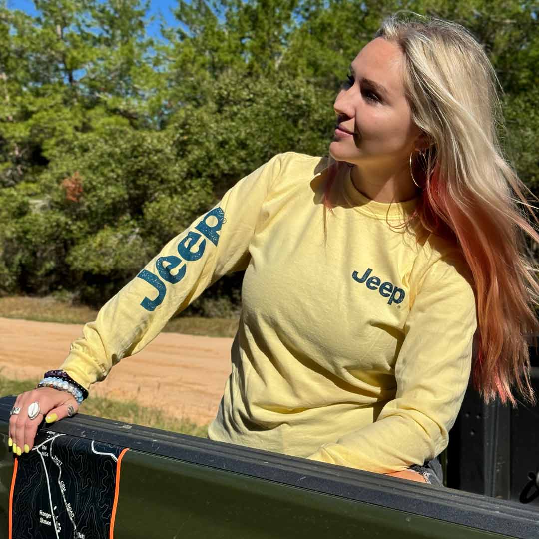 woman wearing yellow long sleeve with jeep logo along the sleeve and on the left chest