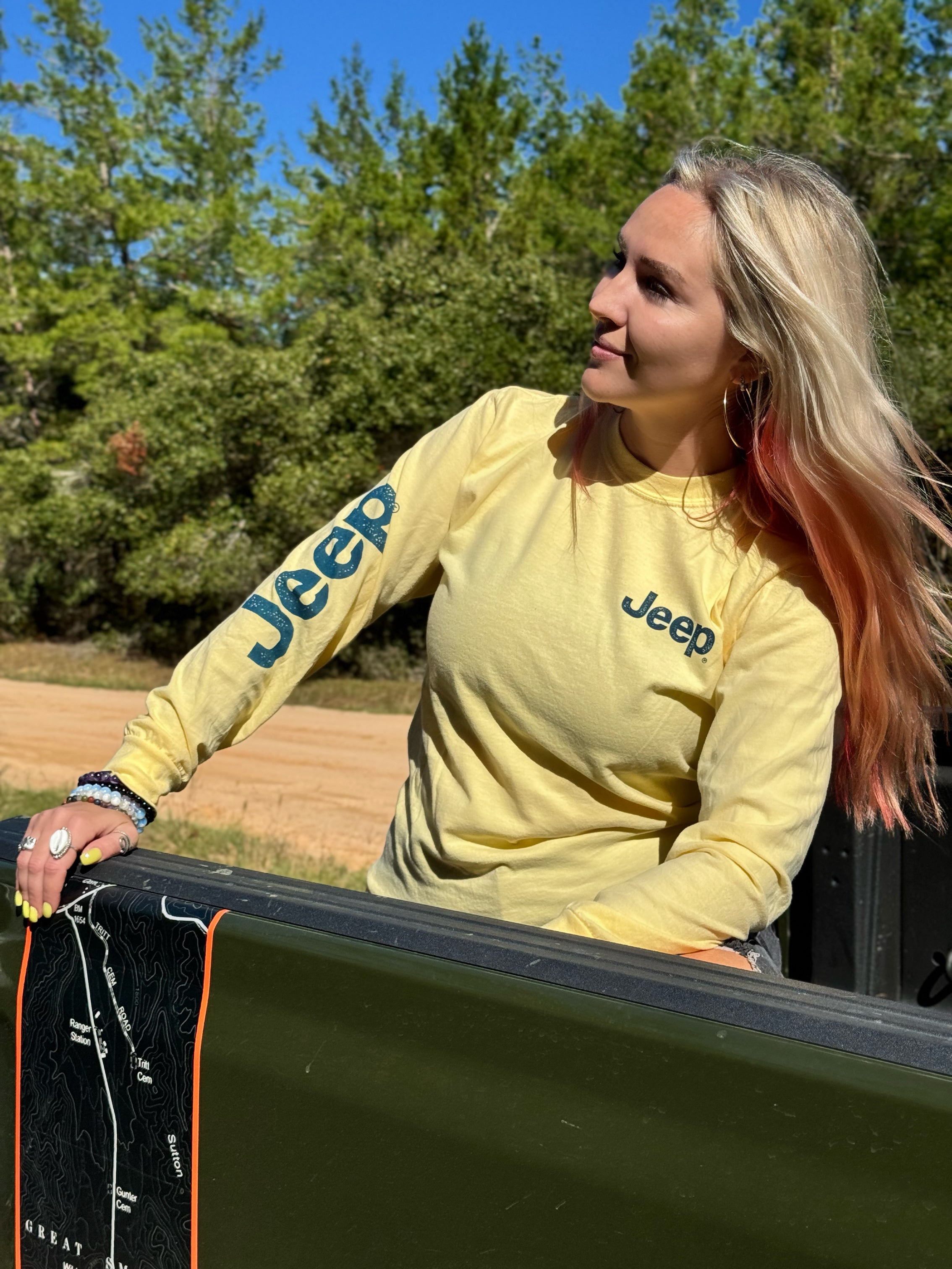 woman wearing yellow long sleeve with jeep logo along the sleeve and on the left chest