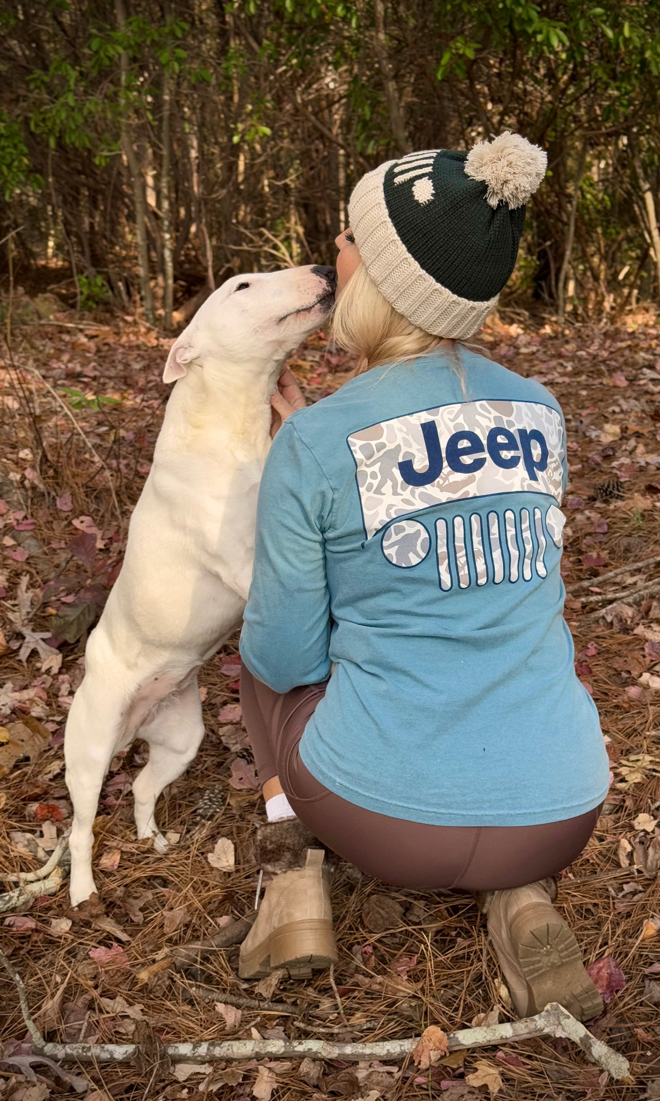 woman wearing jeep beanie and long sleeve shirt while kissing her dog