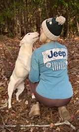 woman wearing jeep beanie and long sleeve shirt while kissing her dog