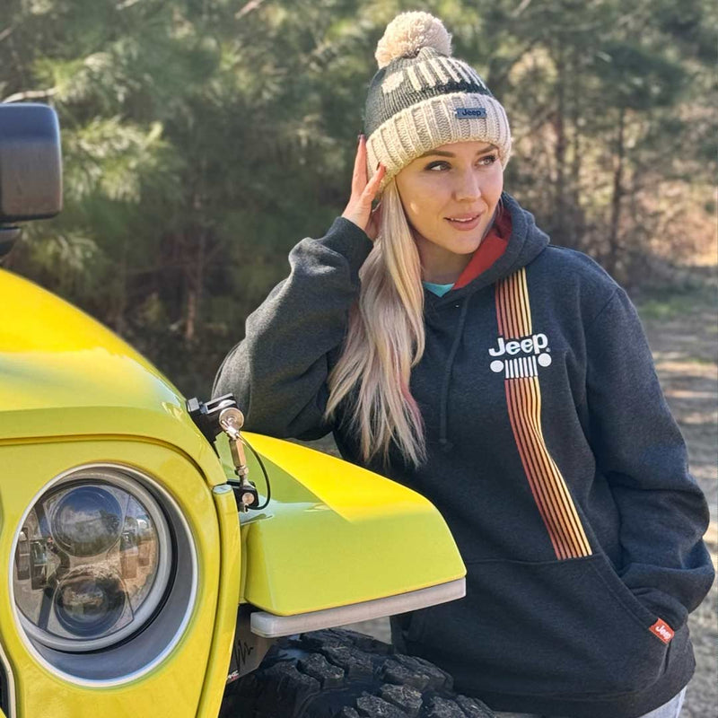 girl wearing jeep hoodie and beanie hat leaning on a jeep