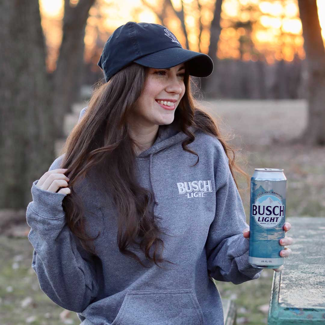 Girl in Busch Light hoodie with logo on left chest having a drink