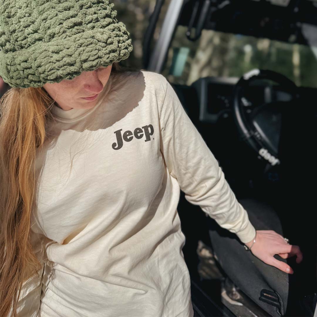 Woman wearing an ivory Jeep long sleeve shirt and green beanie