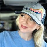 woman wearing a grey heathered jeep hat with embroidered mountains and sun on it