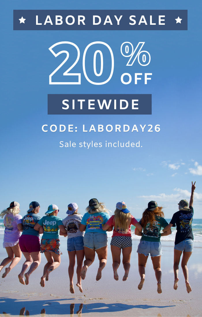 Labor Day sale with large white text reading '20% OFF SITEWIDE' and 'CODE: LABORDAY26' over a beach scene. A group of people in colorful t-shirts are jumping on a sandy beach under a blue sky.